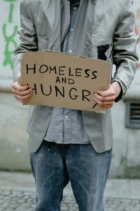 Person holding a 'Homeless and Hungry' sign, depicting urban poverty.