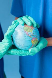 Two people in blue scrubs and gloves holding a globe, symbolizing global health care and environmental protection.